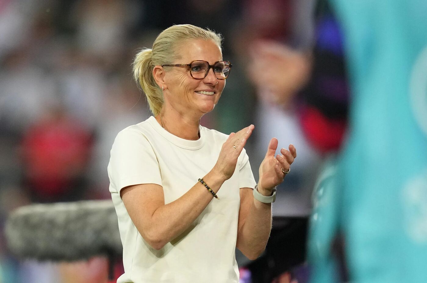 A treinadora da seleção feminina da Inglaterra, Sarina Wiegman, aplaude a atuação de sua equipe durante partida.