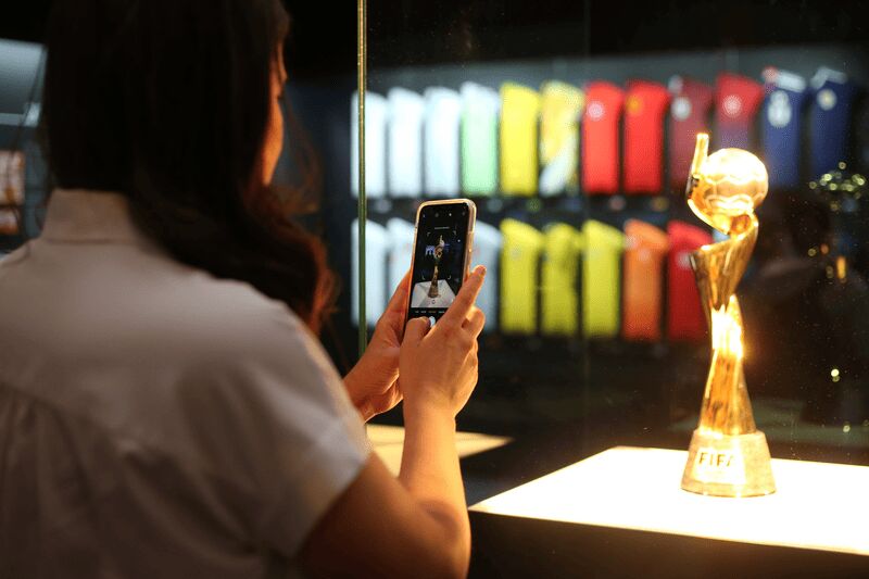 Visitante fotografa a taça da Copa do Mundo Feminina na exposição The Women's Game, em Paris.