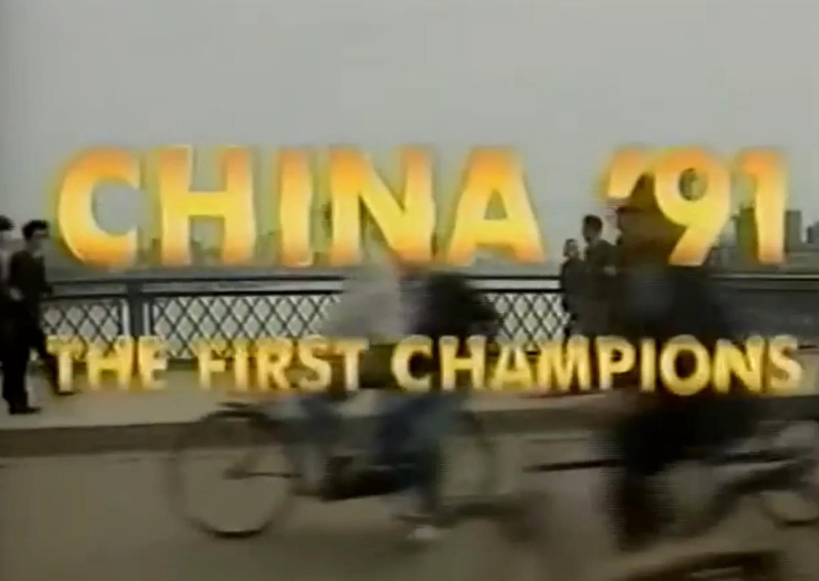 Letreiro CHINA '91 do primeiro Mundial feminino da FIFA, com dois rapazes passando de bicicleta na frente