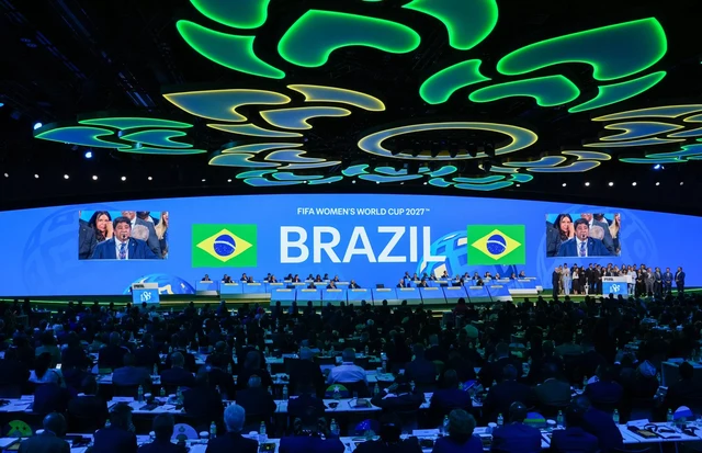 Plenário lotado do 74º Congresso da FIFA em Bangkok, com o telão anunciando FIFA Women's World Cup 2027 Brazil entre duas bandeiras do Brasil